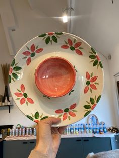 a person holding up a plate with flowers on it in front of a counter top