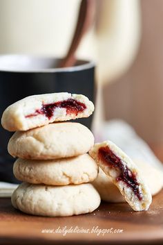 a stack of cookies with jam on them next to a coffee cup and saucer