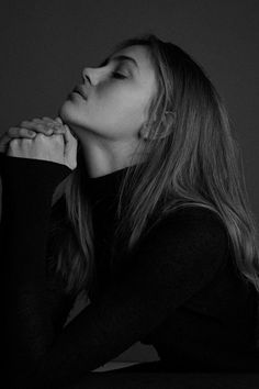 a black and white photo of a woman with her hand on her chin looking up