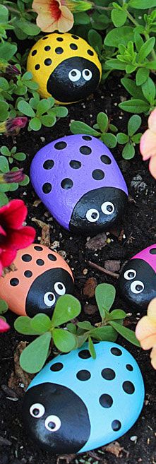 painted rocks in the shape of ladybugs surrounded by flowers