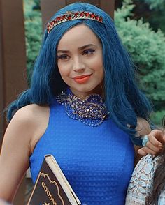 two women standing next to each other wearing blue wigs and holding books in their hands