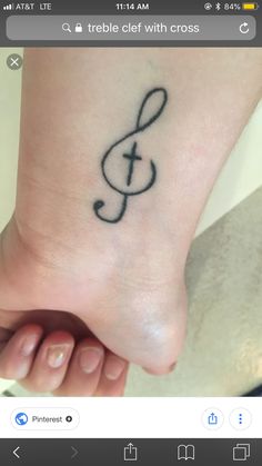 a small tattoo on the foot of a person with a cross and treble in it