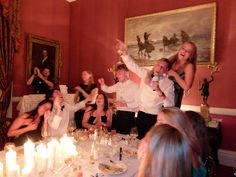 a group of people sitting around a table with candles in front of them and one person standing up