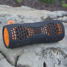 an orange and black speaker sitting on top of a rock