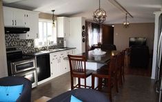 a kitchen and dining room with an open floor plan, white cabinets, black counter tops, and dark wood chairs