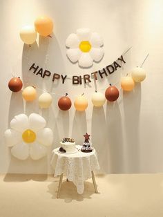 a birthday cake on a table in front of balloons that spell out the word happy birthday