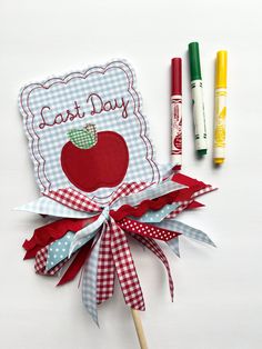 an apple themed teacher's day card next to crayons and markers