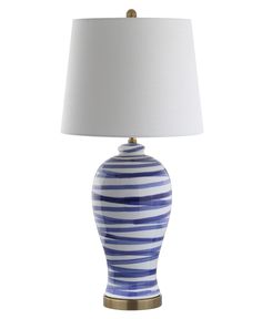 a blue and white striped lamp with a white shade on the top, sitting against a white background