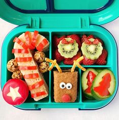 a bento box filled with fruit, vegetables and crackers to look like a face