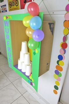 an open cardboard box with balloons and streamers hanging from the ceiling in front of it