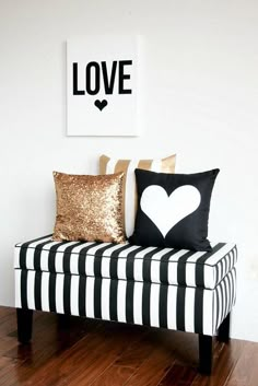 a black and white bench with two pillows on it's back, in front of a love sign