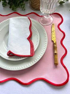 the place setting is ready to be served with red and white napkins, silverware, and gold - plated utensils