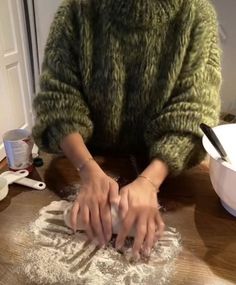 a woman sitting at a table making dough