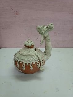 a ceramic teapot sitting on top of a white table next to a pink wall