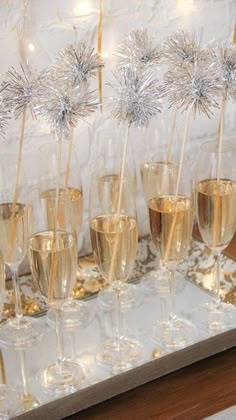 champagne flutes are lined up on a tray with snowflakes and sparklers in them