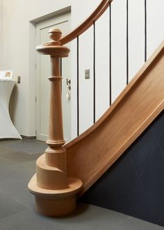 a wooden stair case next to a white wall