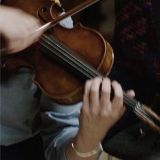 a close up of a person holding a violin in their hands and playing the violin