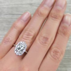 a woman's hand holding an engagement ring with a large diamond in the center