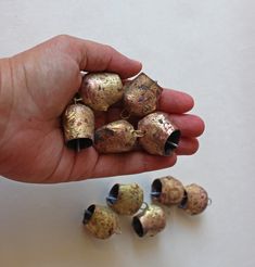 a hand holding several small metal bells in it's left hand next to each other