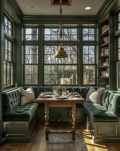 a living room with green couches and wooden tables in front of two large windows