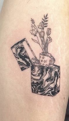 a black and white image of a vase with flowers in it sitting on the back of a woman's thigh