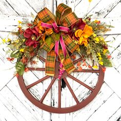 a wheel decorated with flowers and ribbons on the side of a white wooden door,