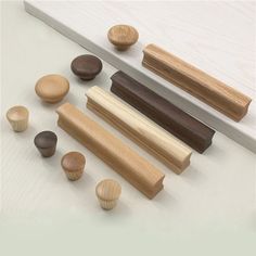 several different types of wooden objects on a white counter top with wood handles and knobs