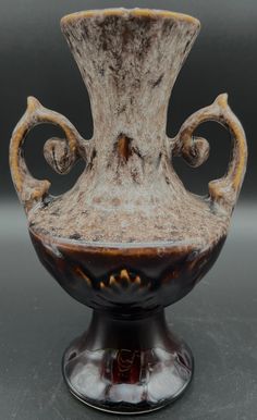 an old vase is sitting on a black surface with swirly designs around the base