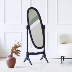 an oval mirror sitting on top of a stand next to a potted plant in front of a white wall