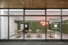 the inside of a restaurant with green tile walls and wooden tables, stools and chairs