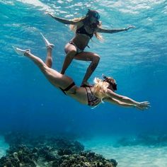 two women in bikinis are diving under the water