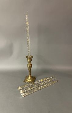 a gold colored candle holder sitting on top of a white table next to two smaller candles