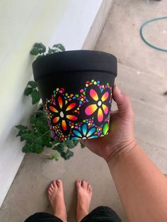 a person is holding a flower pot with their feet on the ground next to a plant