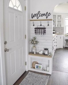 a welcome sign is hanging on the wall next to a door in a white kitchen