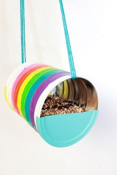 a colorful bird feeder hanging from a string with birdseed in the bottom and inside