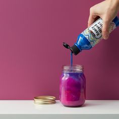 a person is pouring colored liquid into a jar