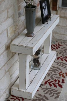 a white shelf with two vases on top of it next to a brick wall