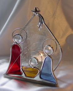 three colorful glass ornaments sitting on top of a white cloth