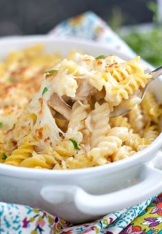 a spoon full of macaroni and cheese being lifted from the casserole dish