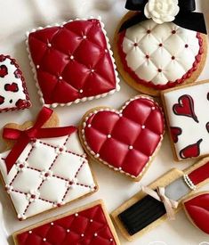 decorated cookies are arranged on a plate with red and white decorations, such as heart - shaped cookies