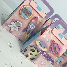 two pink boxes with space themed decorations on them, one opened and the other closed