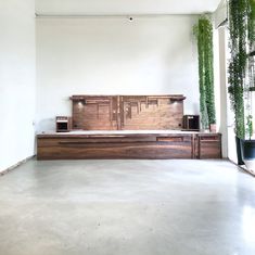 a large wooden bench sitting in the middle of a room with potted plants on it