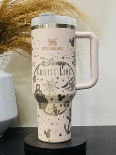 the disney cruise line travel mug is sitting on a table next to a potted plant