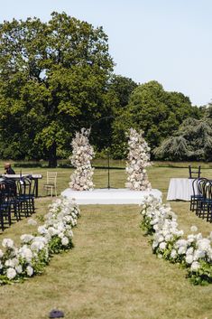 an outdoor ceremony setup with white flowers and greenery