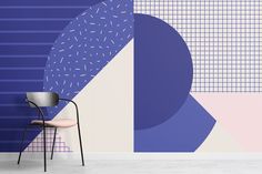 a chair sitting in front of a blue and pink wall with geometric shapes on it