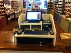 a computer sitting on top of a desk in a store next to a phone and printer