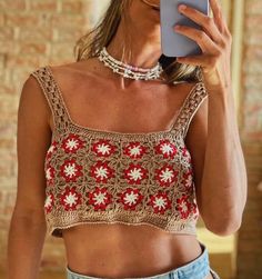 a woman taking a selfie while wearing a crop top and denim shorts with her cell phone