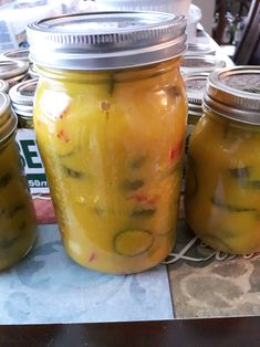 three jars filled with pickles sitting on top of a table