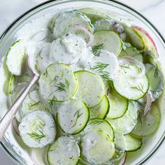 cucumber and dill salad in a glass bowl with a spoon on the side