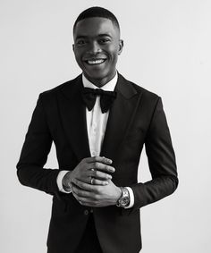 a black and white photo of a man in a tuxedo smiling at the camera